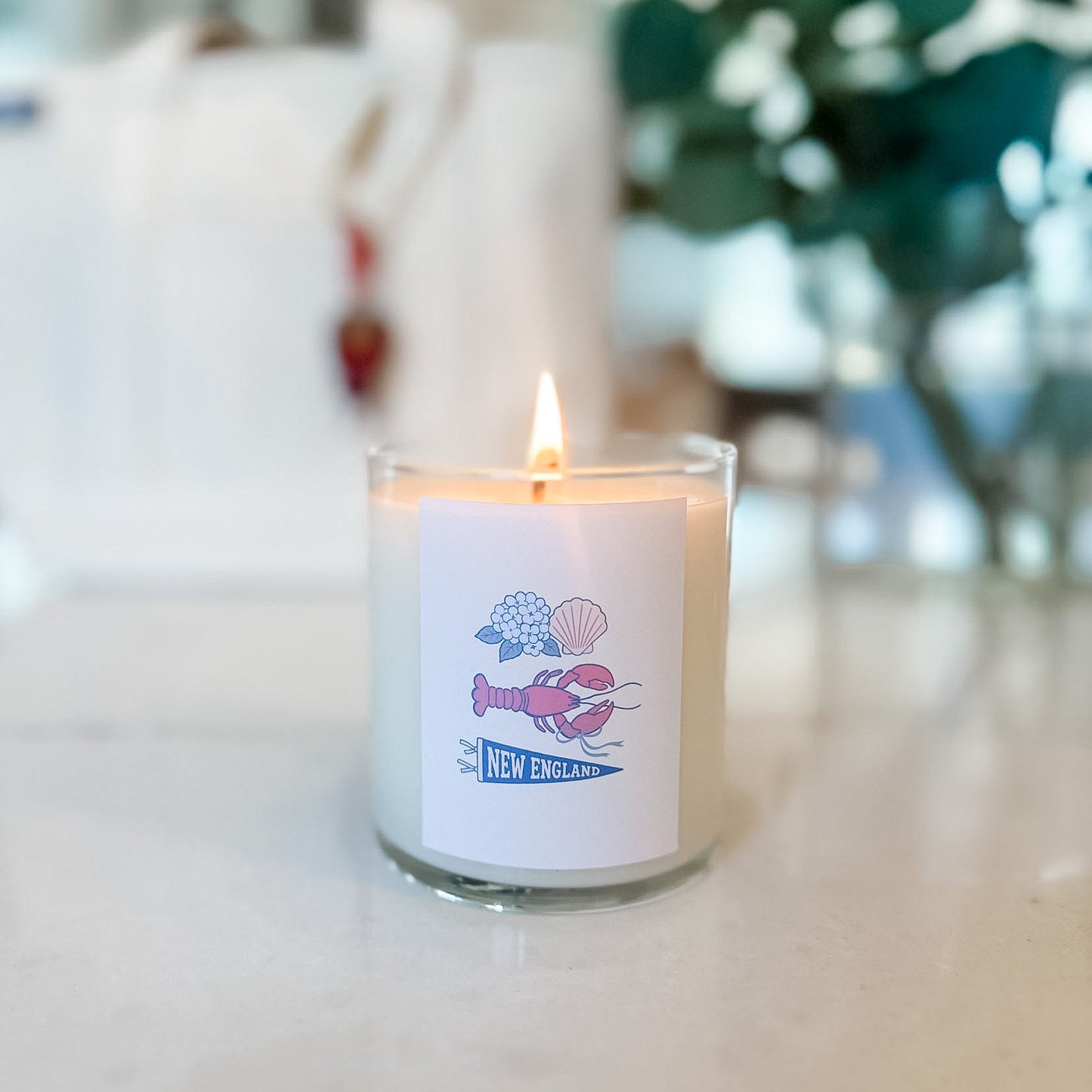 Candle with a label featuring a lobster design on a blurred background