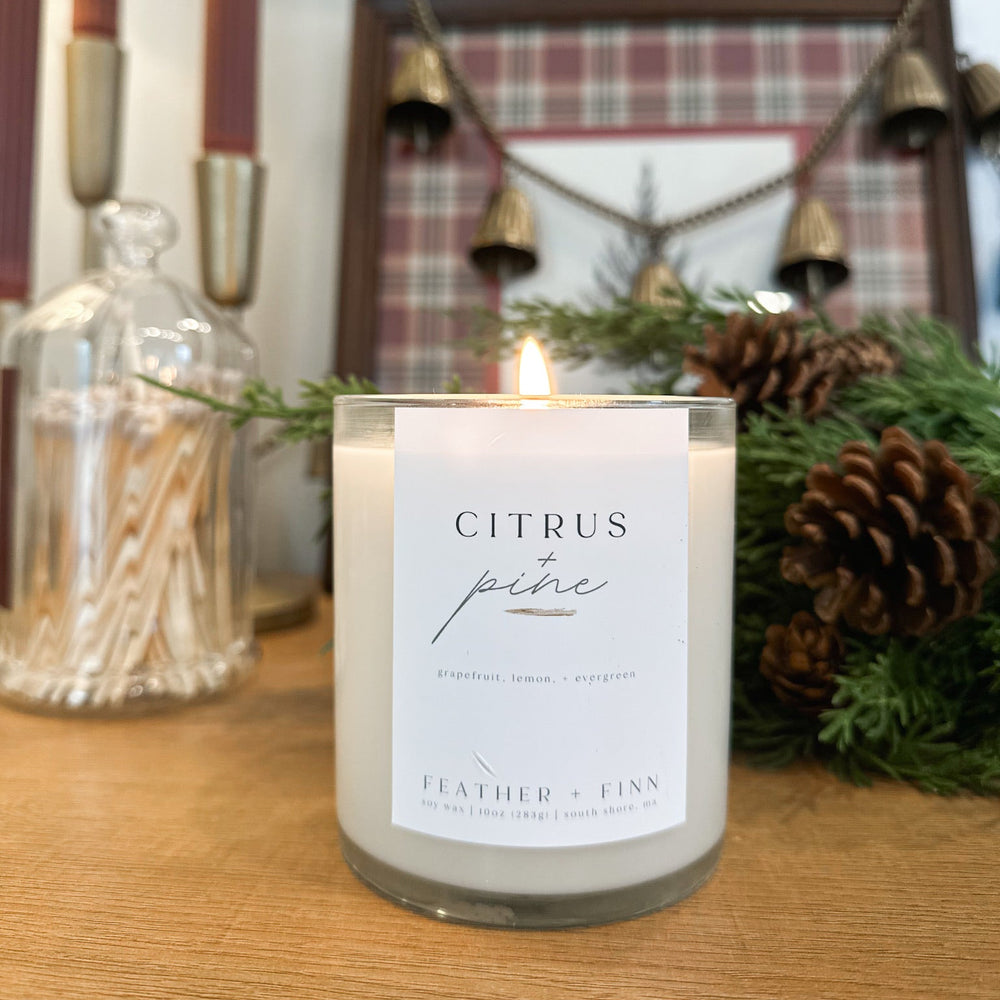 Candle labeled 'Citrus Pine' on a wooden surface with decorative elements in the background